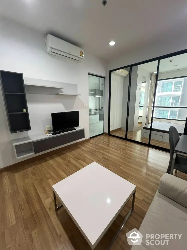 Modern living room with wooden flooring and glass partition in stylish apartment