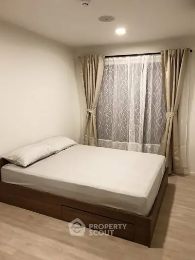 Cozy bedroom with elegant curtains and wooden flooring, perfect for relaxation.