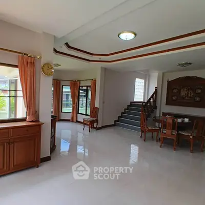 Spacious living room with elegant wooden furniture and large windows for natural light.