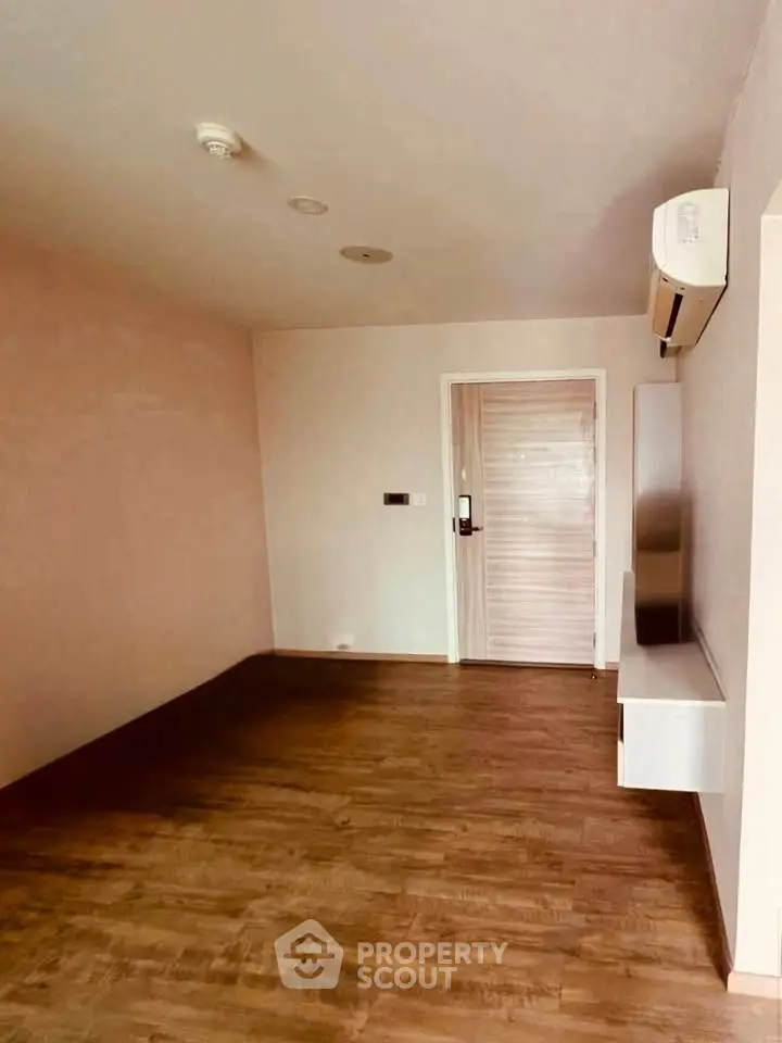 Spacious empty room with wooden flooring and air conditioning, perfect for customization.