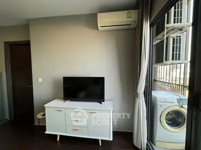 Modern living room with TV, air conditioner, and washing machine near balcony.