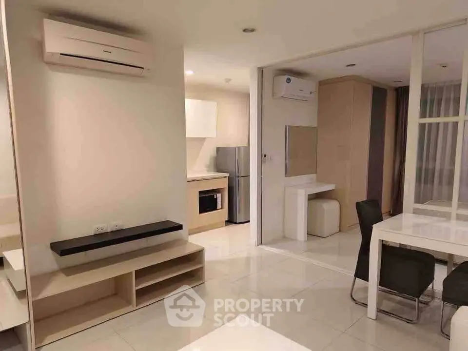 Modern open-plan living area with sleek kitchen and dining space, featuring air conditioning and stylish furnishings.