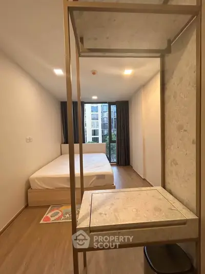 Modern bedroom with large window and minimalist decor in a stylish apartment.