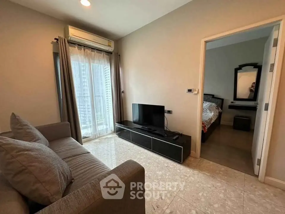Modern living room with sleek furniture and city view, adjacent to a cozy bedroom.
