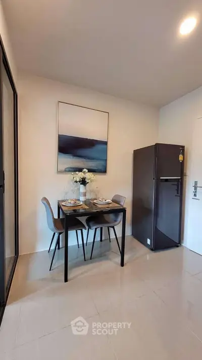 Modern dining area with sleek table and chairs, adjacent to a stylish refrigerator, perfect for cozy meals.