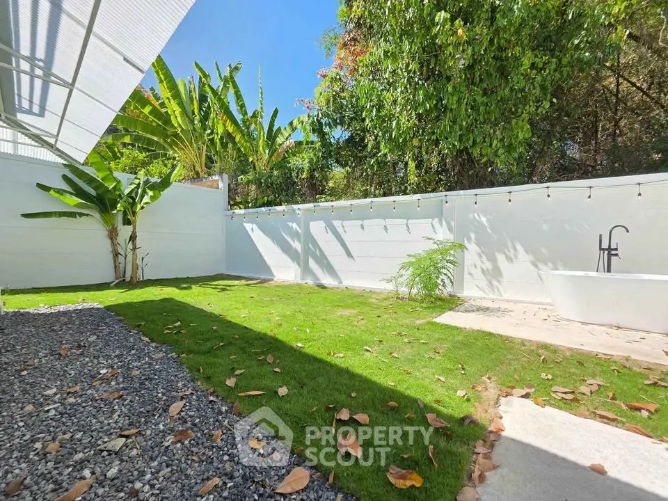 Charming garden with lush greenery and modern outdoor bathtub, perfect for relaxation.