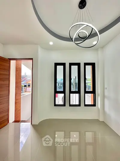 Modern interior with unique ceiling light and large windows, showcasing sleek design and natural light.