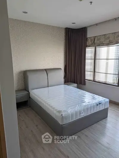 Spacious bedroom with modern bed and large windows offering natural light.