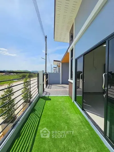 Modern balcony with artificial grass and sliding glass doors in a contemporary home.