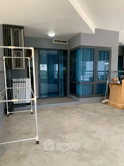 Spacious balcony with modern glass doors and ample storage space.