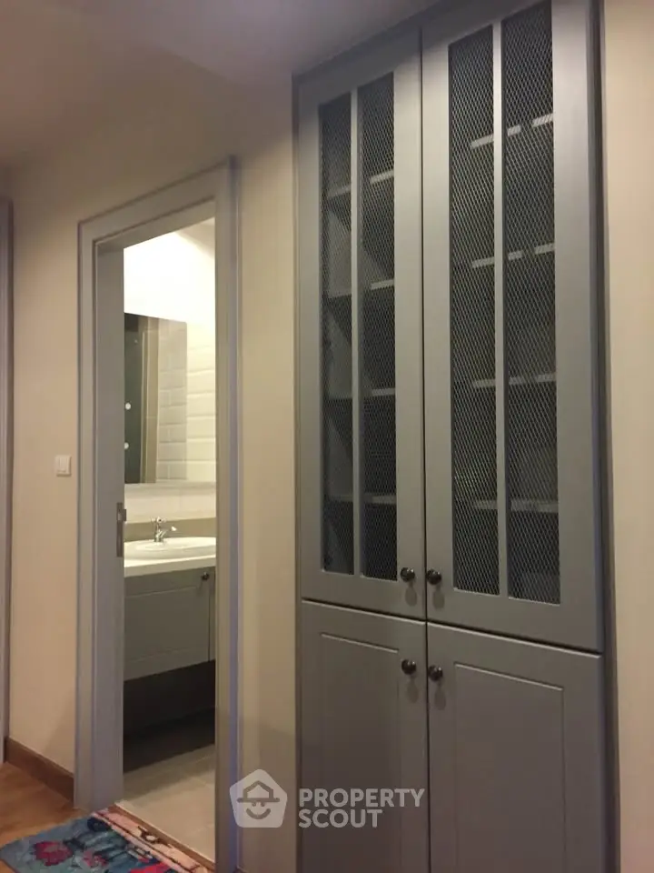 Modern interior hallway with built-in storage and view into a sleek bathroom.