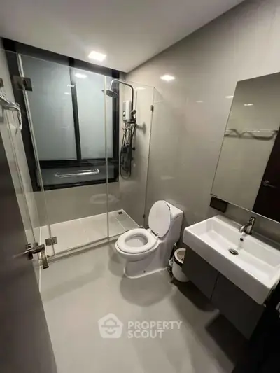 Modern bathroom with glass shower and sleek fixtures in contemporary apartment.