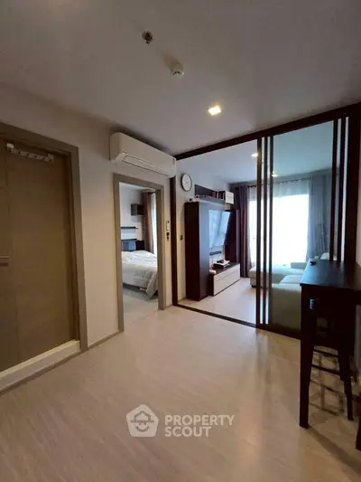 Modern apartment interior with open living space and bedroom view, featuring sleek design and natural light.