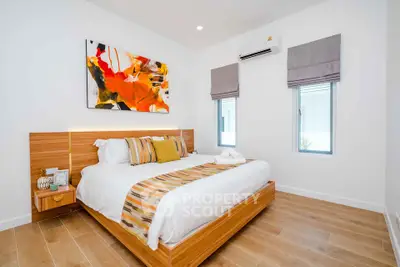 Modern bedroom with stylish decor and wooden flooring, featuring a vibrant abstract painting.