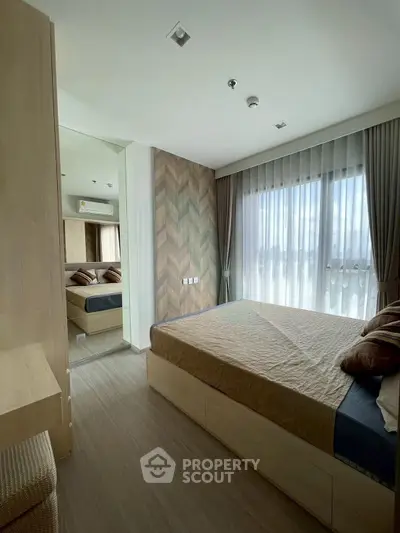 Modern bedroom with stylish decor and large window offering natural light