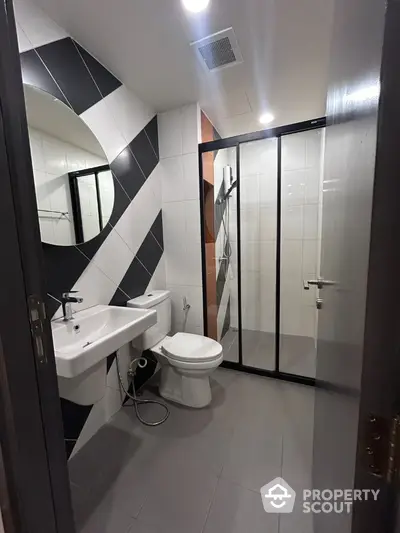 Modern bathroom with stylish black and white tiles and glass shower enclosure