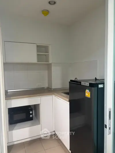 Compact kitchen with modern appliances and sleek cabinetry in a cozy apartment.