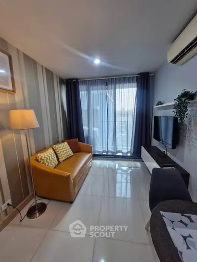 Modern living room with stylish decor, cozy sofa, and natural light from large windows.