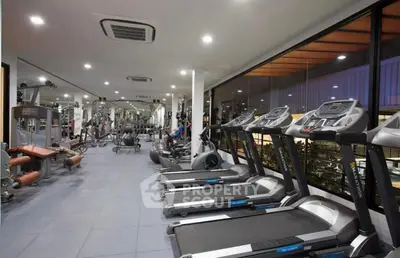 Spacious modern gym with state-of-the-art equipment and large windows for natural light.