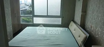 Spacious bedroom with large window offering city views and natural light.
