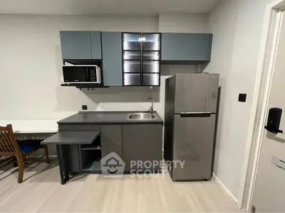 Modern compact kitchen with sleek cabinetry and stainless steel appliances in a stylish apartment.