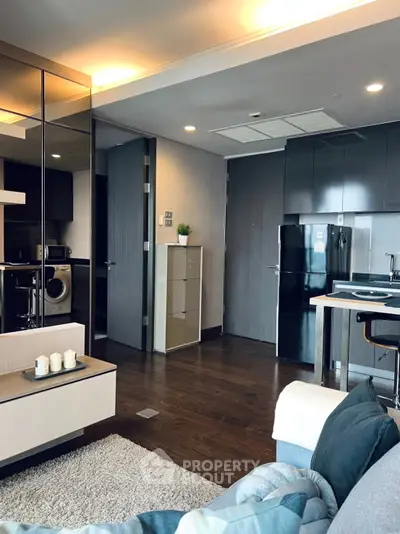 Modern living room with sleek kitchen, dark wood flooring, and stylish decor in a contemporary apartment.