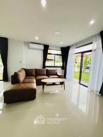 Spacious living room with modern brown sectional sofa and garden view.