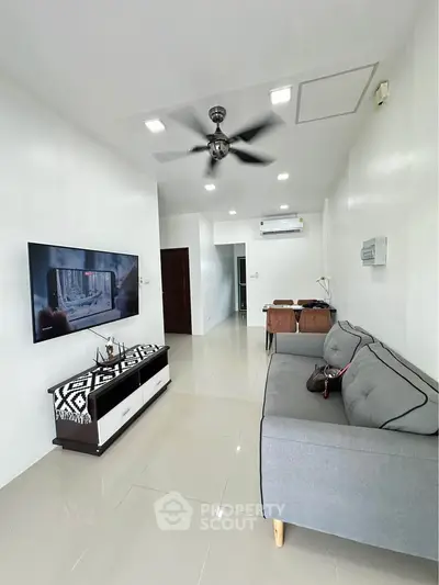 Modern living room with sleek furniture and wall-mounted TV, perfect for relaxation.