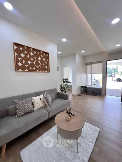 Modern living room with stylish decor and natural light, featuring a cozy gray sofa and chic wooden accents.