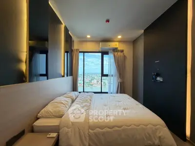 Modern bedroom with large window offering stunning city view, featuring cozy bedding and sleek design.