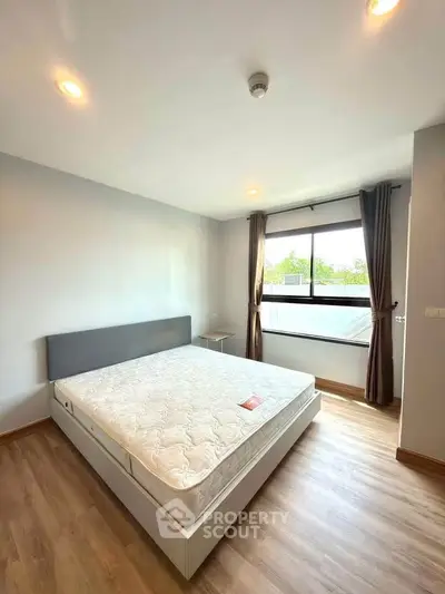 Spacious bedroom with large window and modern design in a bright apartment.