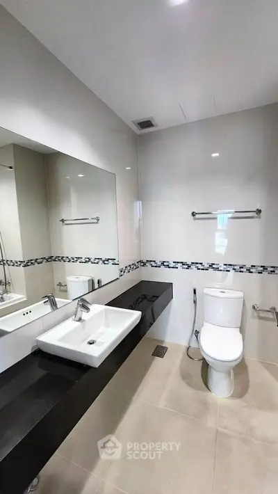 Modern bathroom with sleek fixtures and large mirror in a contemporary apartment.
