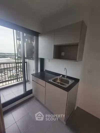 Modern compact kitchen with balcony view in urban apartment