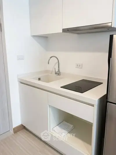 Modern minimalist kitchen with sleek white cabinetry and built-in stovetop