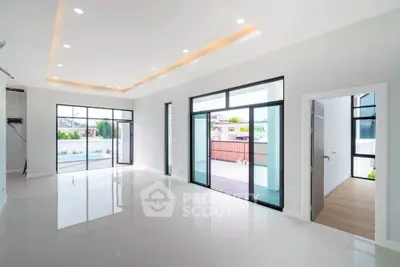 Spacious modern living room with large windows and elegant lighting, offering a bright and airy atmosphere.