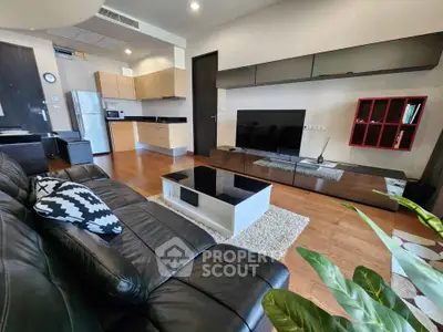 Modern living room with open kitchen, sleek furniture, and hardwood floors.