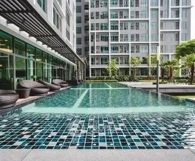 Luxurious modern apartment complex with stunning outdoor pool and stylish seating area.