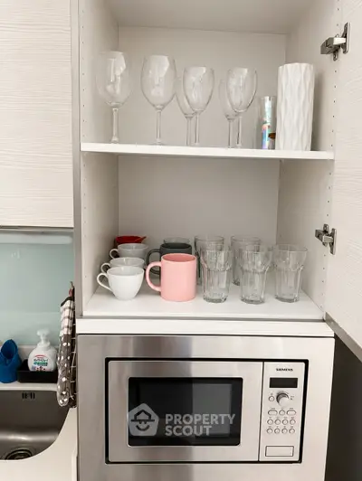 Modern kitchen with built-in microwave and organized glassware cabinet