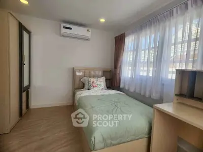 Cozy bedroom with single bed, air conditioning, and ample natural light from large window.