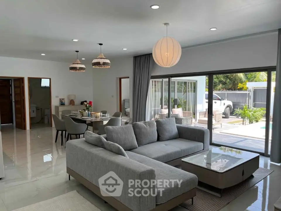 Spacious modern living room with open layout and pool view, featuring elegant decor and ample natural light.