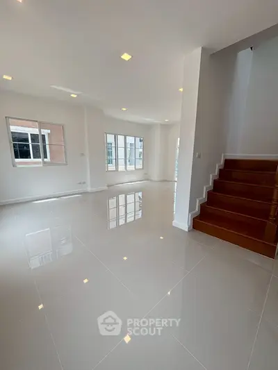 Spacious modern living room with glossy tiled floors and staircase