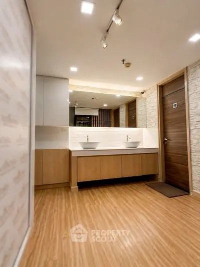 Modern bathroom with dual sinks and wooden flooring in a stylish apartment.