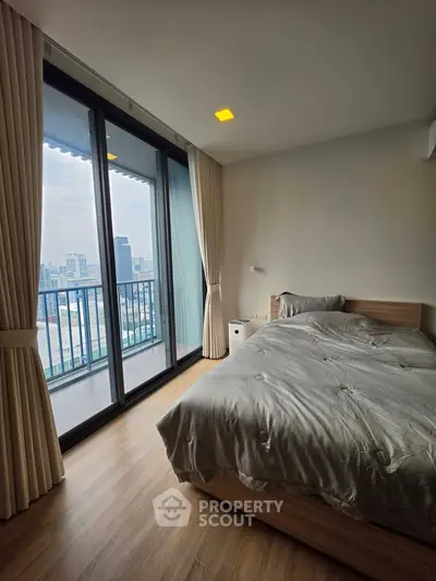 Modern bedroom with city view and balcony access in high-rise apartment