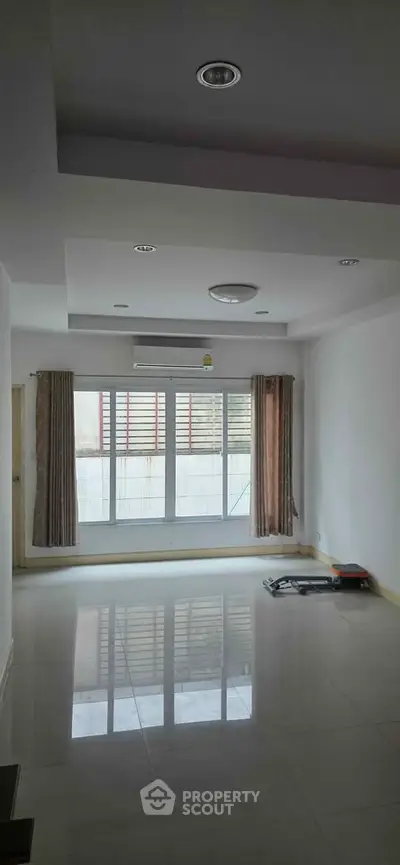 Spacious unfurnished living room with large windows and modern ceiling lights.