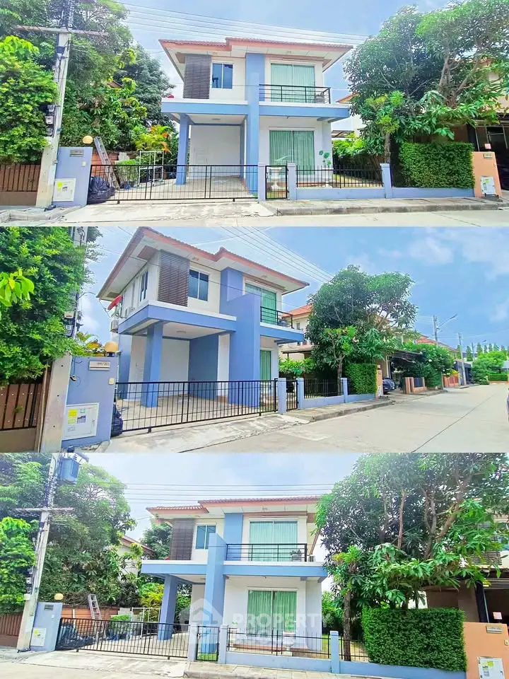Charming two-story blue house with lush greenery and gated entrance in a serene neighborhood.