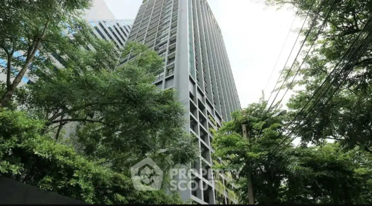 Modern high-rise building surrounded by lush greenery, offering urban living with a natural touch.