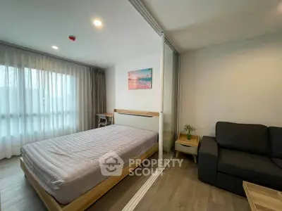 Modern bedroom with large window and cozy seating area in stylish apartment.