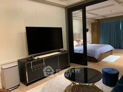 Luxurious modern living room with large TV and elegant bedroom view
