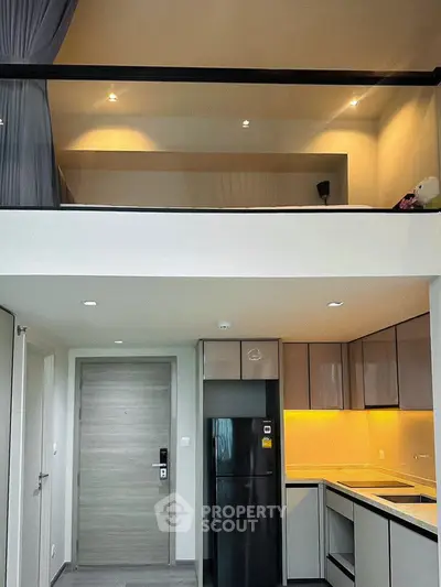 Modern loft apartment with sleek kitchen and mezzanine bedroom, featuring stylish lighting and contemporary design.