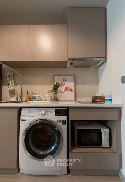 Modern kitchen with washing machine and microwave in compact layout.